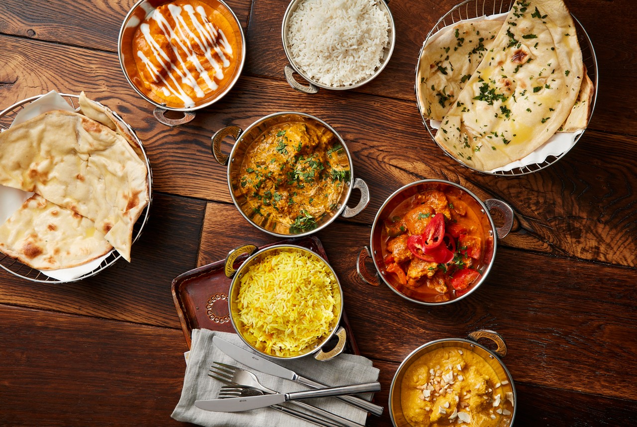 A selection of Indian dishes including, rice, naan bread and a variety of curries.